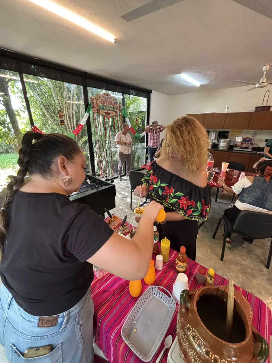 Ale preparando un esquite al momento junto a la olla de barro en un evento